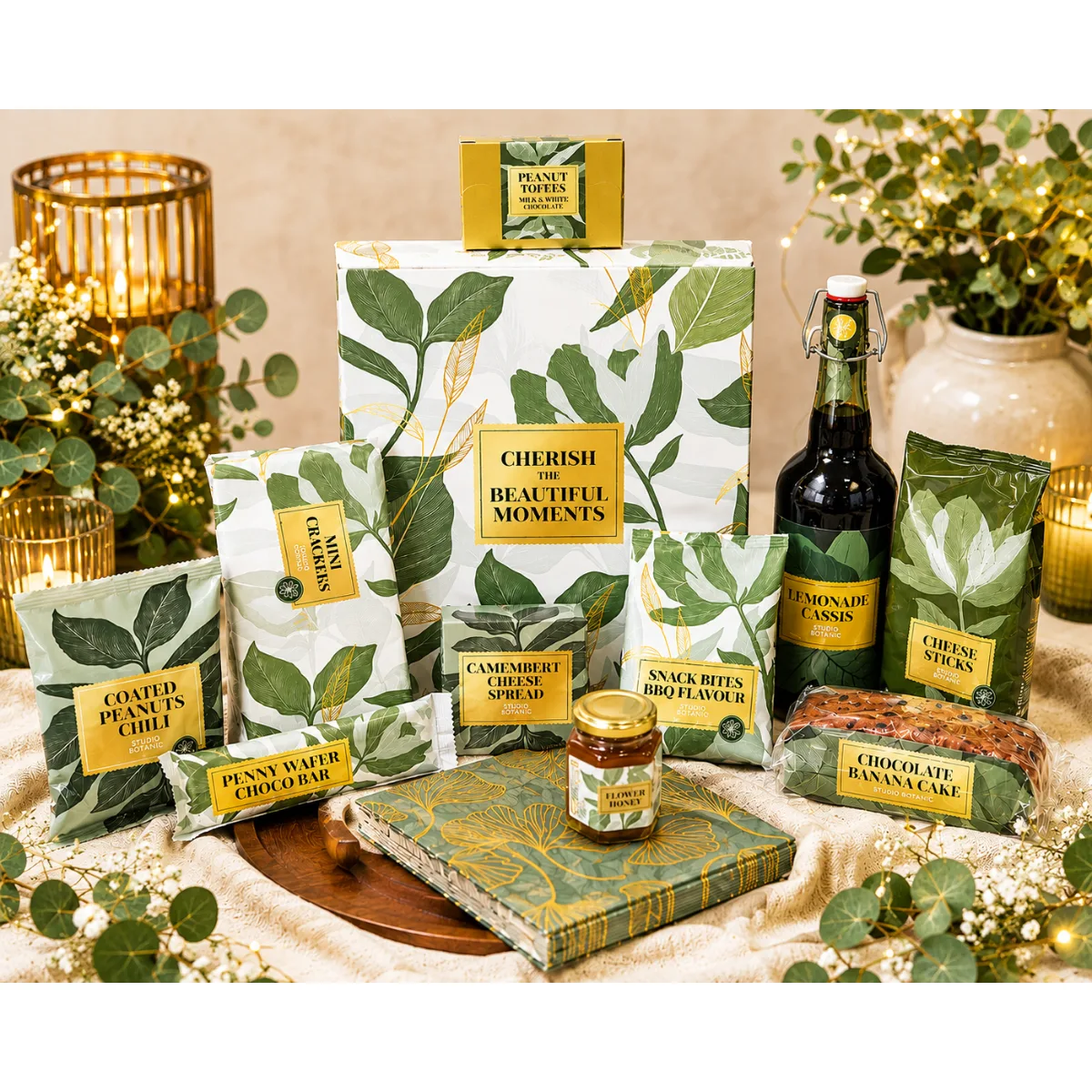 Kerstpakket Bloom & Bites, Gourmet Moments met Studio Botanic limonade, camembert spread, bloemenhoning, bananencake, pennywafelreep, pindarotsjes, mini crackers, BBQ snackbites, borrelnoten en kaasstengels. Origineel borrel kerstpakket 2026 voor medewerkers en zakelijke relaties.